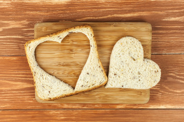 Slice of cereal toast bread with cut out heart shape on wooden