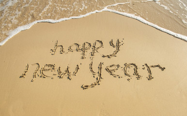 Fototapeta na wymiar happy new year written in the sand