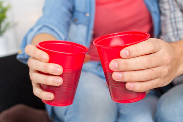 Closeup hands of friends toasting with red plastic cups