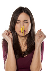 disgusted young woman pinching her nose with a clothespin