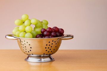 Red and green grapes in a colander