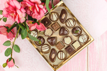 Box with chocolates and pink flowers. Selective focus.