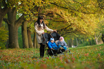 Fototapeta na wymiar mother with children twins on a walk in the autumn park
