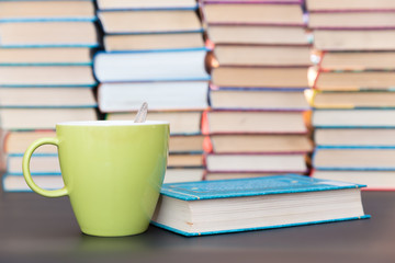 green cup and blue book on a background of books