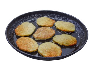 Чугунная сковорода с жарящимися картофельными оладьями