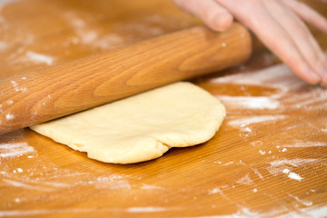 Woman’s hands roll dough on the table