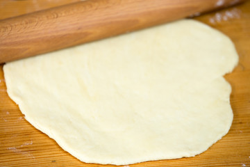 Flattened dough and rolling-pin on the table