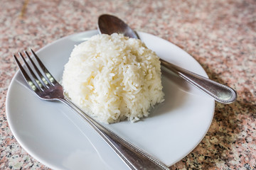 Rice in white dish with silverware. on the marble table