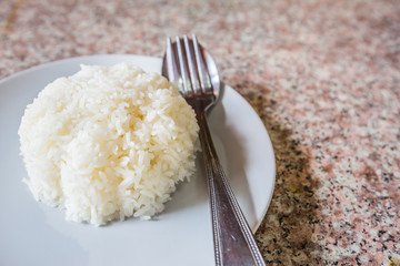 Rice in white dish with silverware. on the marble table