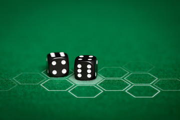 close up of black dice on green casino table