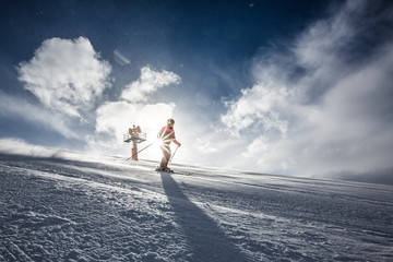 Skifahrer bei Sonnenschein vor Schneekanone