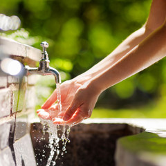 Woman washing hands in a city fountain