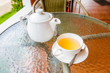 Cup of tea and teapot on glass table