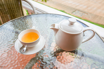 Cup of tea and teapot on glass table