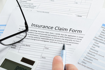 Hand With Pen On Insurance Claim Form