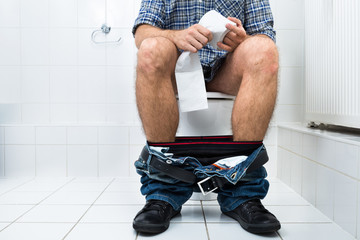 Man In Toilet Holding Tissue Paper Roll - obrazy, fototapety, plakaty