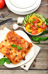 Portion of tasty lasagna on wooden table