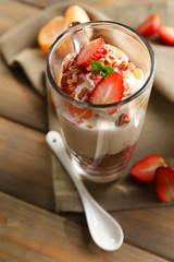 Healthy layered dessert with muesli and strawberries on table