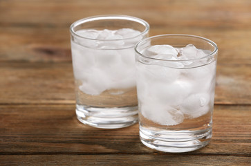 Glasses with ice cubes on wooden table
