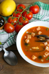 Tasty soup with mussels, tomatoes and black olives in bowl