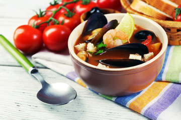 Tasty soup with shrimps, mussels, tomatoes and black olives in