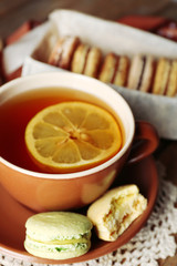 Colorful macaroons with cup of tea on wooden background