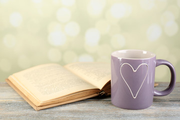 Cup of tea and book on table, on light background