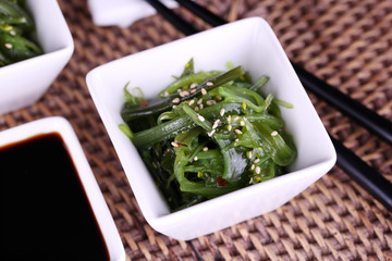 Seaweed salad with say sauce on wicker mat background