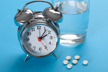 Pills With Glass Of Water And Alarm Clock