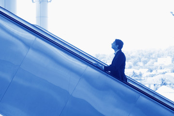 Indian businessman ascending escalator - Powered by Adobe