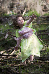Naklejka na ściany i meble little girl dressed as a fairy with soap bubbles
