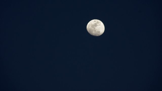 Time-lapse footage of the rising moon with the sky become dark