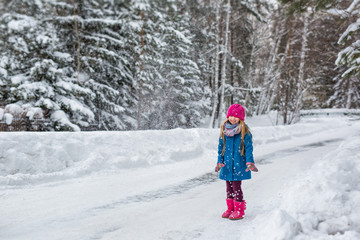 Fototapeta na wymiar Little Girl throws snow up and smiles