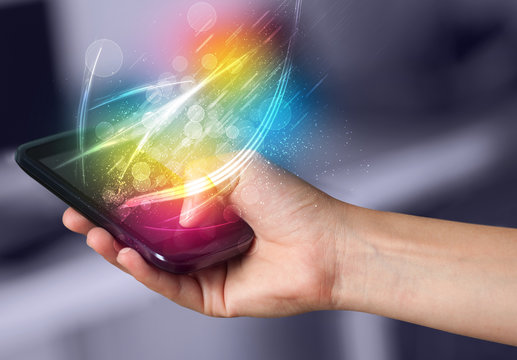 Hand holding smart phone with abstract glowing lines