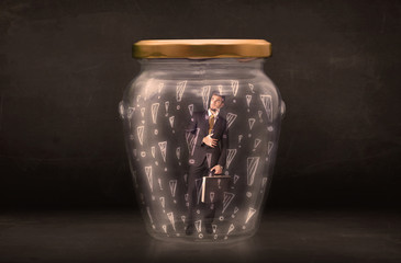 Business man trapped in jar with exclamation marks concept