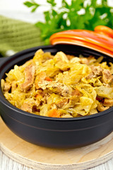Cabbage stew with meat in black roaster on board
