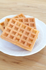 Delicious sweet waffle in ceramic white plate on wood table