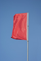 Red flag flying on blue sky