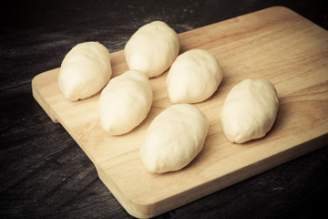 Pieces of dough on the wooden board. Toned