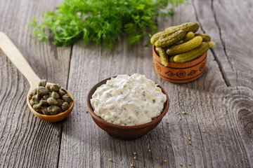 tartar sauce in a gravy boat on a wooden surface