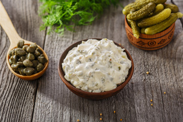 tartar sauce in a gravy boat on a wooden surface