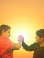Two teenage boys shaking hand against sunny sky