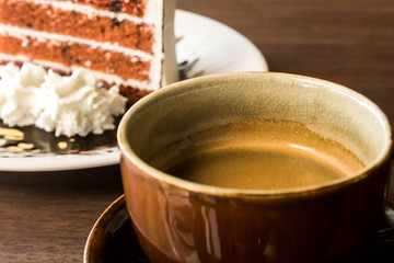 Coffee cup with slice of cake on wood table in cafe