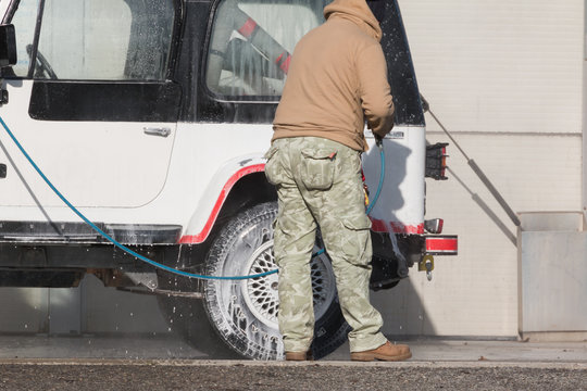 Man washing his car with a jet of water