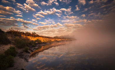 Fototapeta na wymiar misty morning on the river and clouds reflected in water