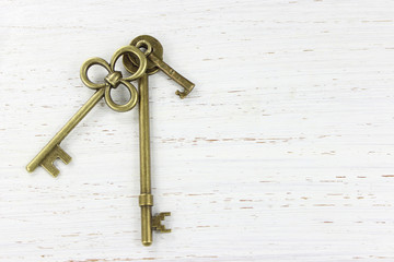Three brass keys on a white distressed wood background