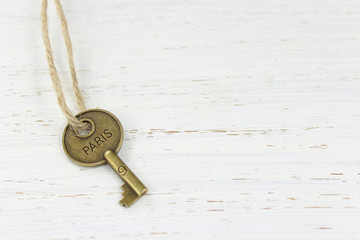Paris key on a white distressed wood background