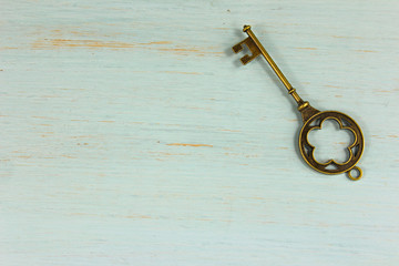 Antique brass key on a pale green distressed wood background.