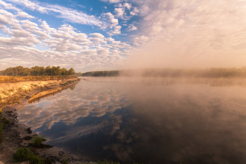 misty morning on the river and clouds reflected in water
