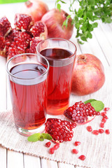 Ripe pomegranates with juice on table on light background